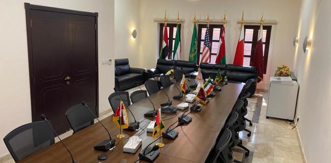 Conference room with table, chairs. Flags are displayed on tables and on flag poles.